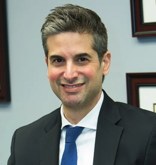 A man in a suit and tie smiling confidently, exuding professionalism and approachability.