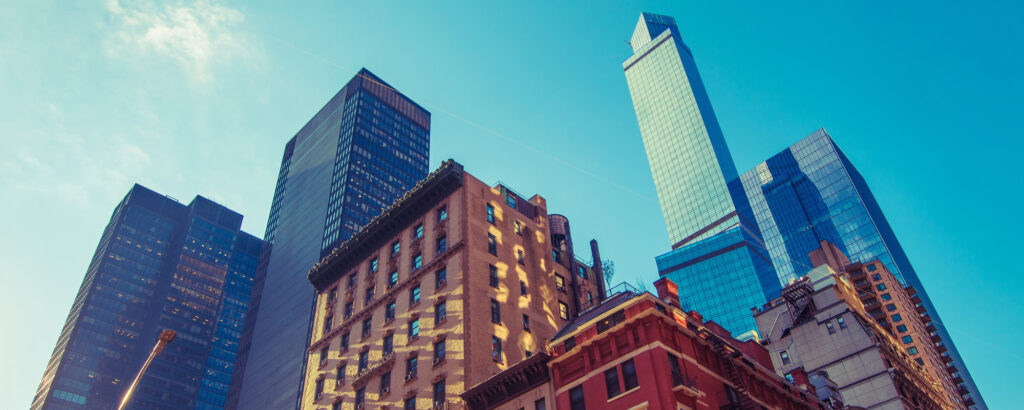 New York City skyline featuring iconic skyscrapers and buildings against a clear blue sky.