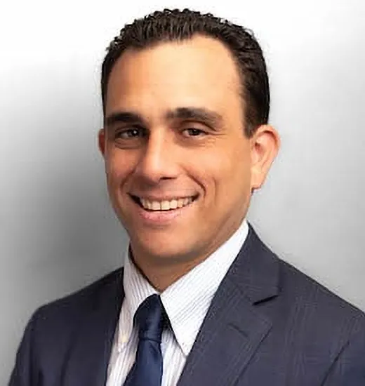 A man in a suit and tie smiling confidently, exuding professionalism and approachability.