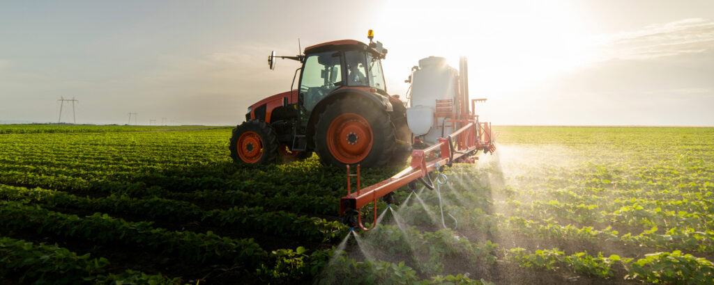 A tractor spraying water across a lush green field, enhancing crop growth and irrigation efficiency.