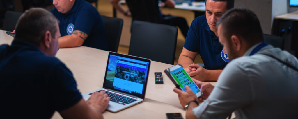 Three men engaged in work at a table, each using a laptop for collaboration and discussion.