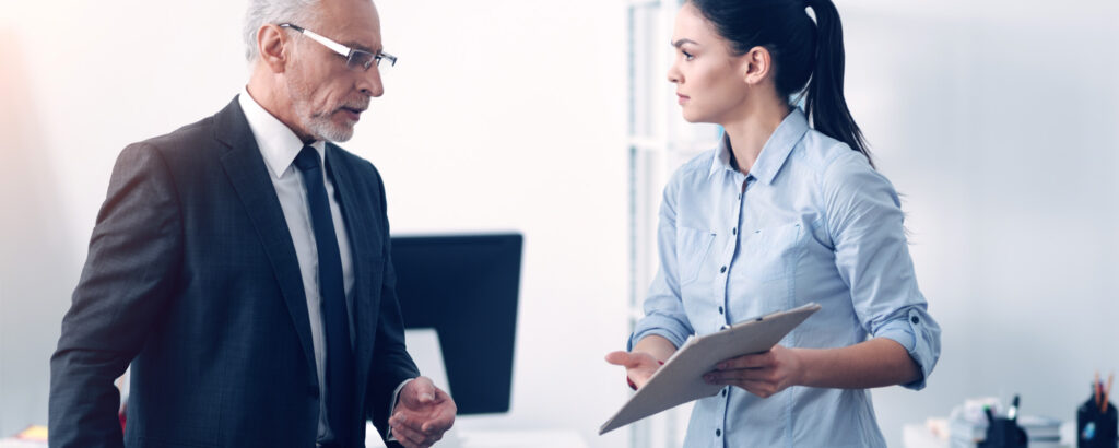 A man and woman engage in a conversation in a modern office setting, surrounded by professional decor and furnishings.