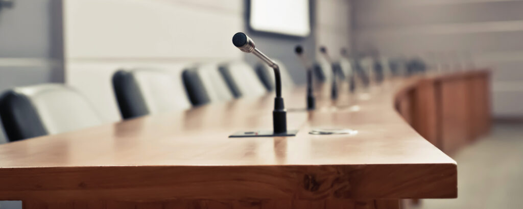 A conference table set with microphones and chairs, ready for a meeting or discussion among participants.