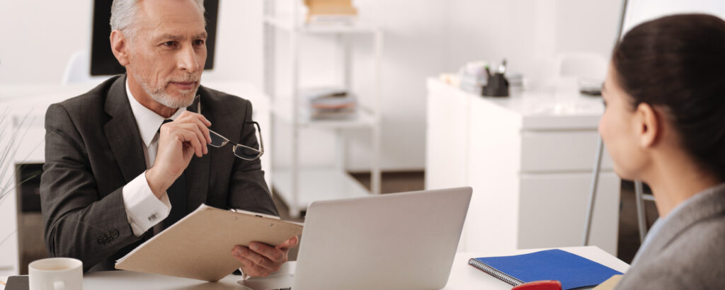 A man and woman in business attire collaborate at a desk, engaged in a professional discussion.