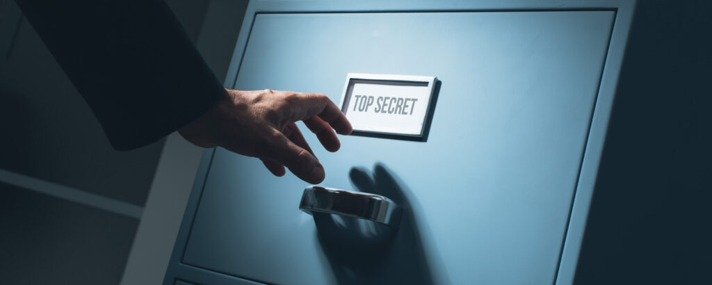 A person using a key to open a file cabinet, revealing organized documents inside.