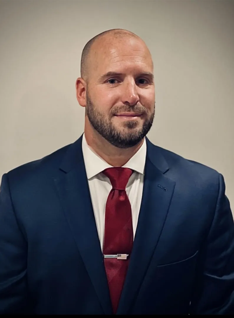 A bald man wearing a suit and a red tie, exuding professionalism and confidence.