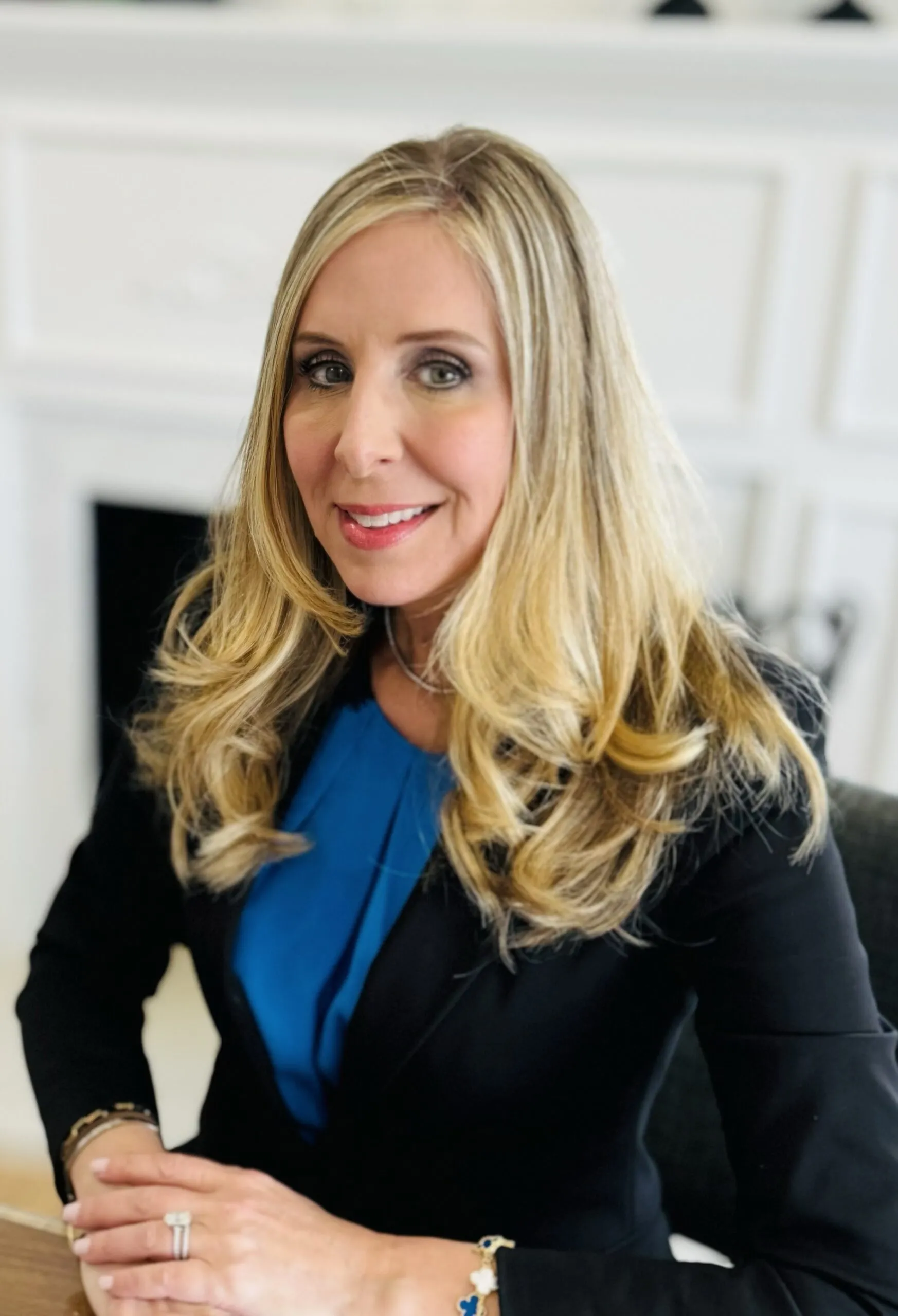 A professional woman in a business suit seated at a desk, focused on her work with a laptop in front of her.